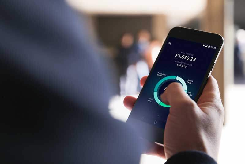Een hand met een smartphone tegen een achtergrond met pictogrammen en infographics||||Fintech startups are making it big in finance|